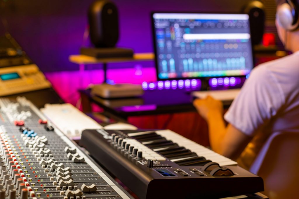 Recording studio with guy sitting in front of the computer working on recording and editing software
