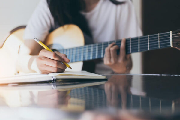Girl holding guitar writing in notebook
