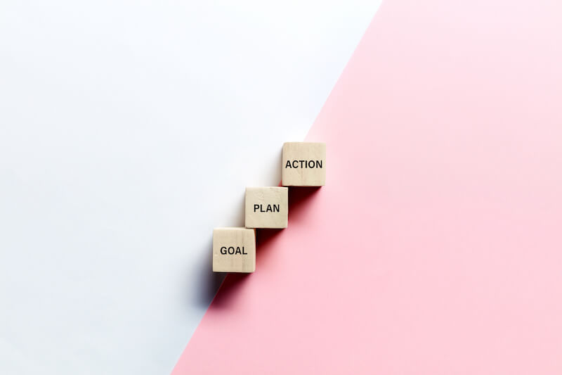 3 wooden cubes with the words goal, plan, and action written on them.