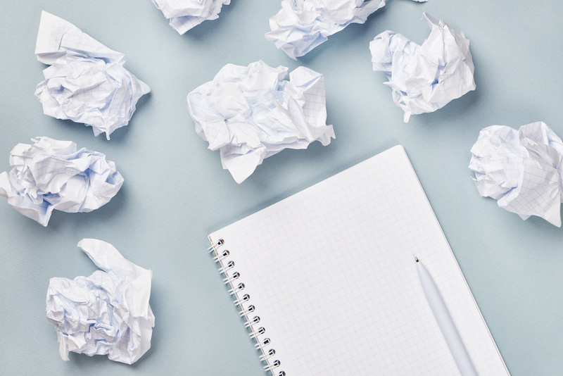Notebook and pen surrounded by crumpled paper balls