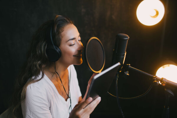 Woman singing into a mic in a recording studio