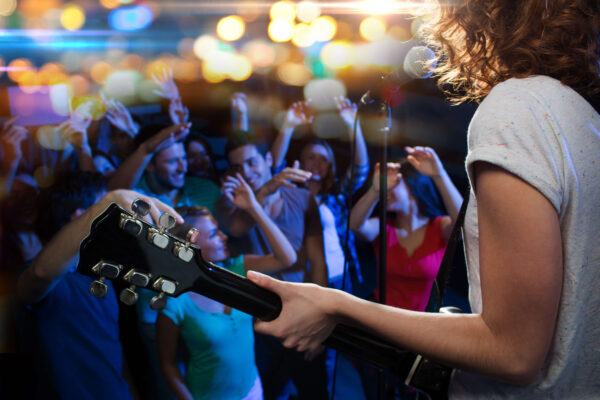Female vocal artist playing her guitar in fron of a crowd