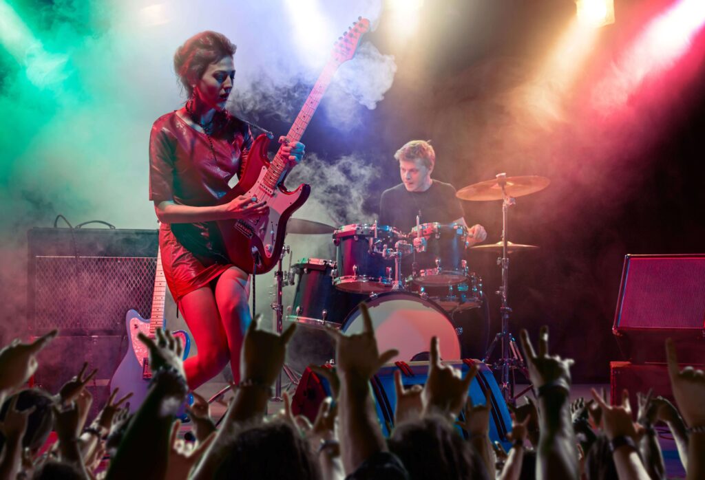 female artist playing guitar in front of fans at a gig