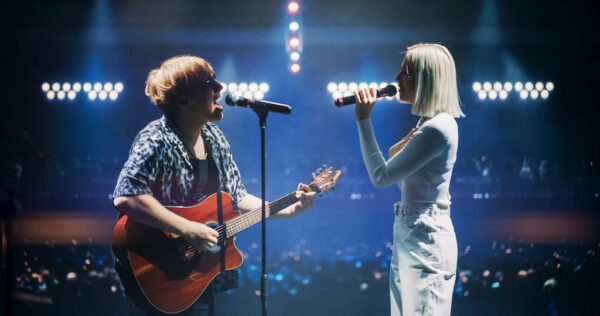 Pop Duo Collaboration With a Male Singer Playing Acoustic Guitar and Female Star Singing on Stage. Folk Guitarist Strums Passionately While RnB Female Performer Sings with Heartfelt Emotion