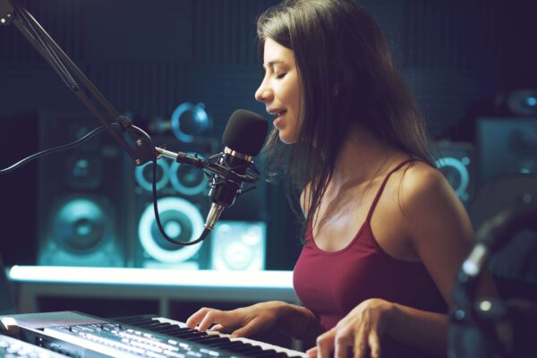Young brunette woman singing into mic in recording studio